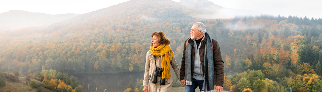 older couple walking in the hills, holding hands.